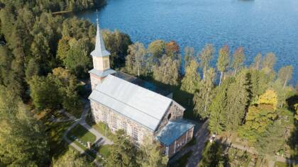 Karjalohjan kirkko Puujärven rannalla aurinkoisena päivänä.