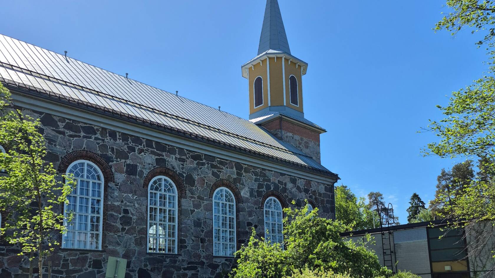 En stenkyrka på sommaren under blå himmel