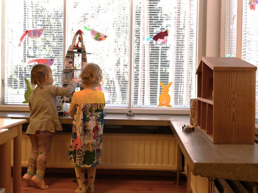 Två flickor leker framför fönstret.