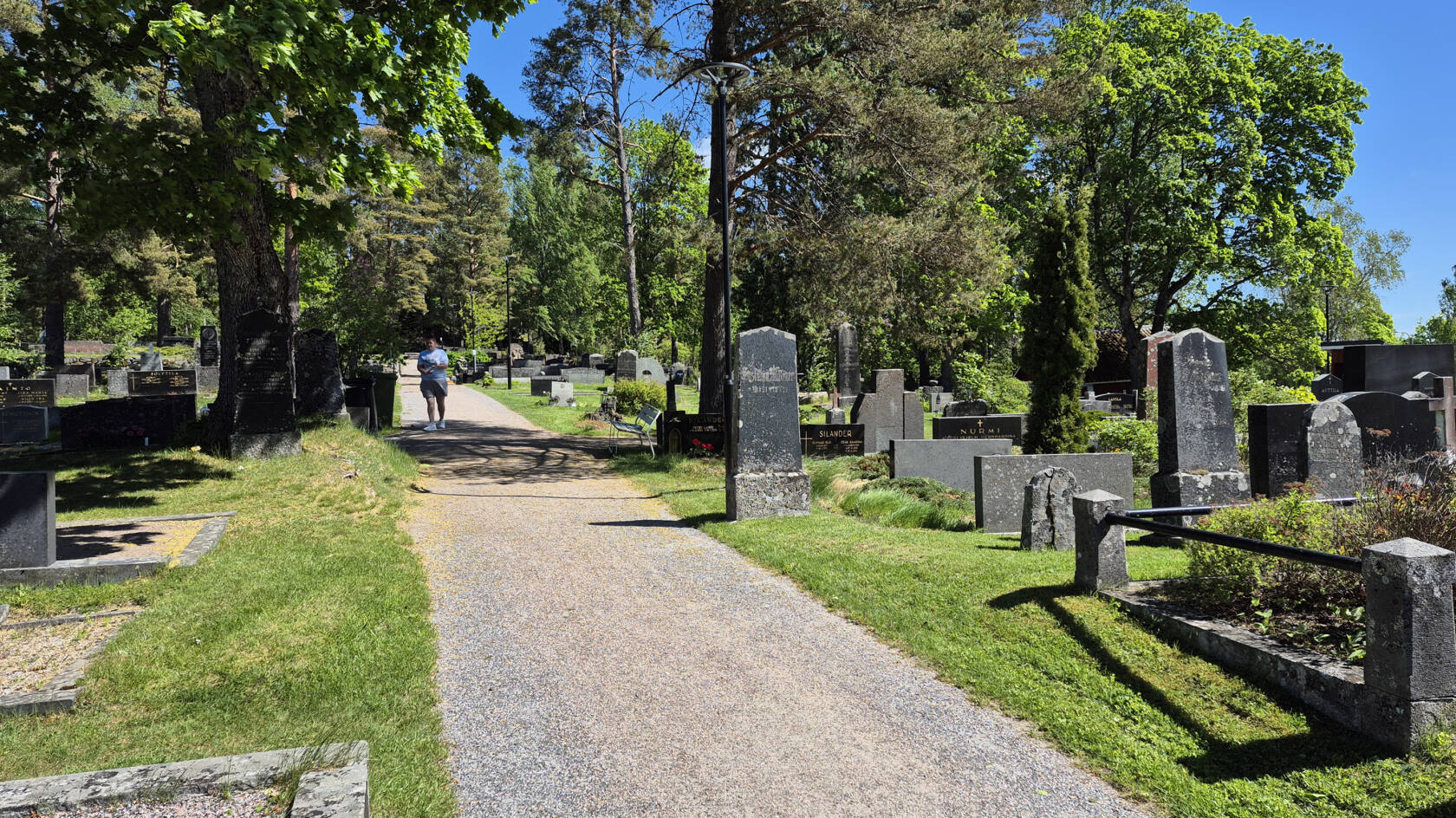 En kyrkogård. I mitten en sandgång.
