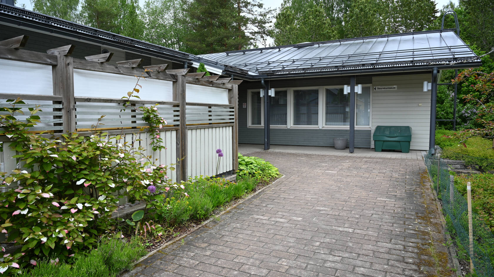 En vit byggnad. En stenbelagd gång leder dit.