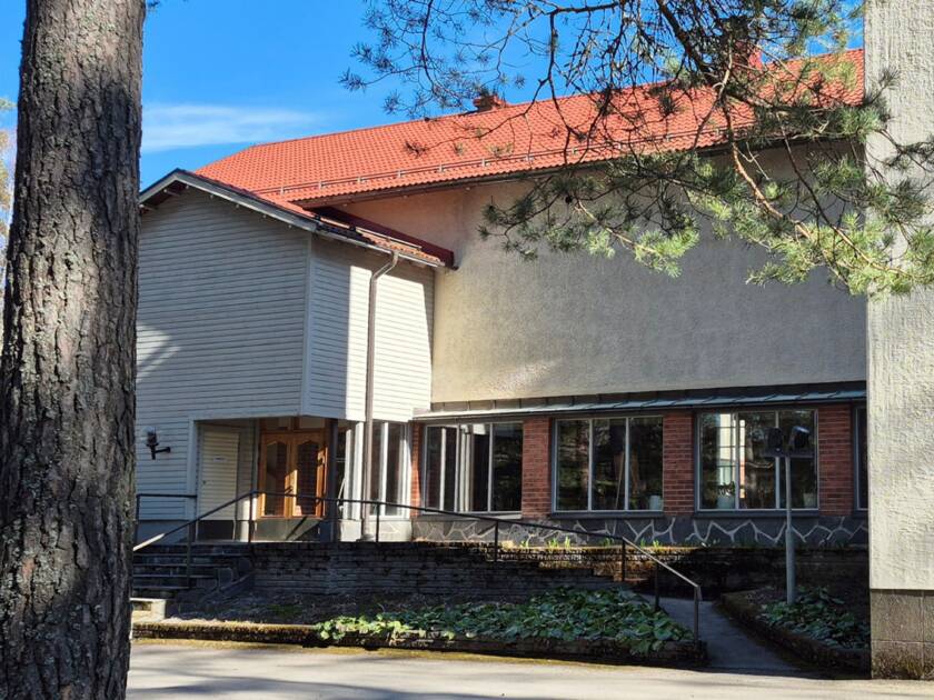 Virkkalan kirkko sivusta, kirkkosalin pääovien puolelta kuvattuna. vasemmassa reunassa puun runko.