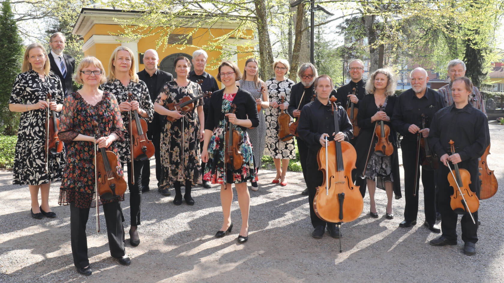 Collegium Musicum Lohja orkesterin jäsenet keväisellä hautausmaalla. Heillä on soittimet käsissään.