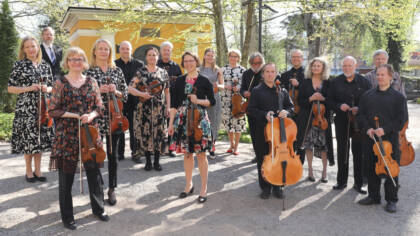 Collegium Musicum Lohja orkesterin jäsenet keväisellä hautausmaalla. Heillä on soittimet käsissään.