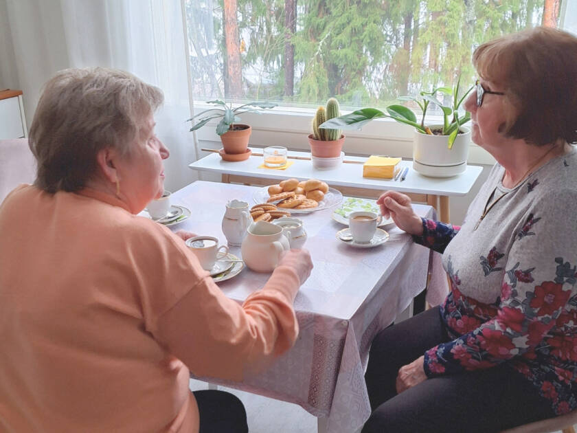 Kaksi naista istuu kahvipöydässä.