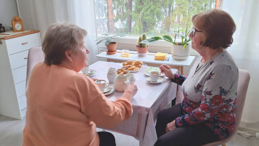 Kaksi naista istuu kahvipöydässä.