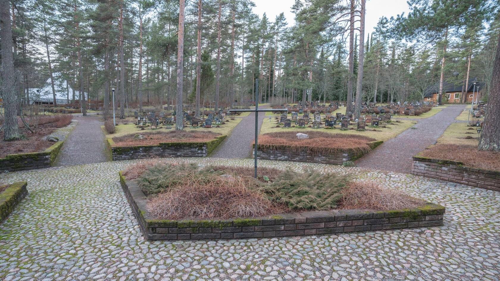 Risti-muistomerkki ja hautakiviä.